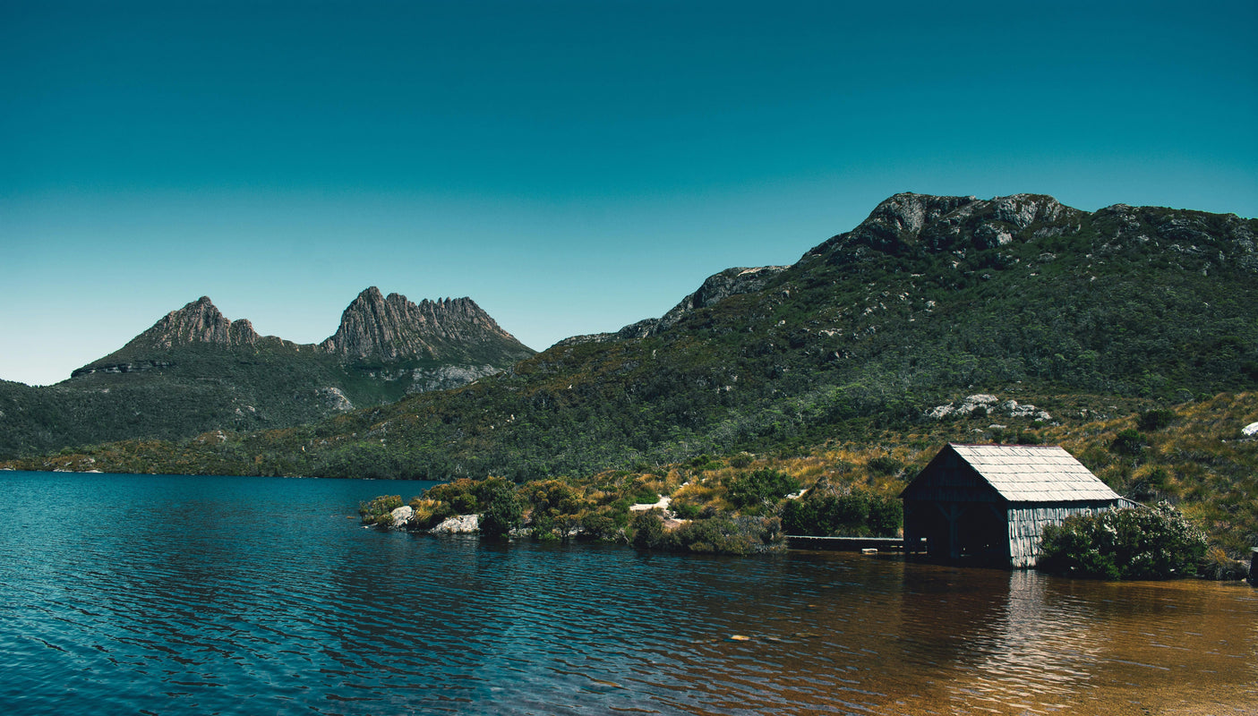 cabin by the water in front of mountains